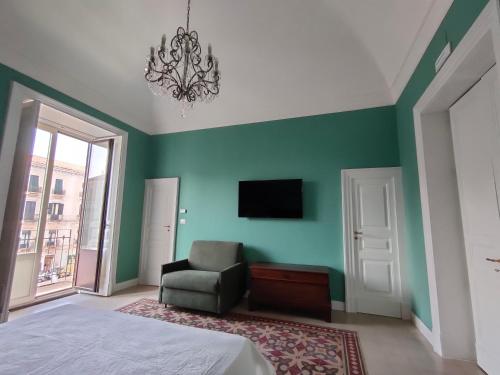 ein Schlafzimmer mit grünen Wänden, einem Stuhl und einem TV in der Unterkunft Finestre in piazza in Catania