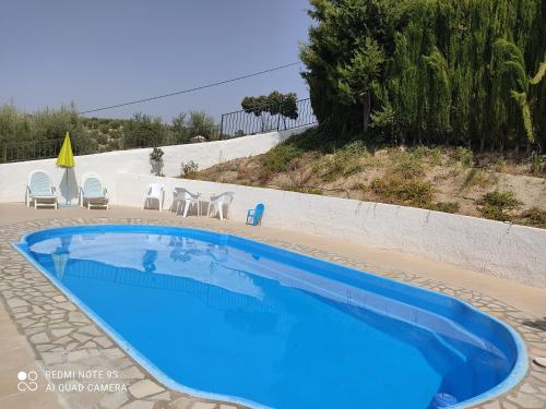 a blue swimming pool with chairs and a table at Alojamiento rural El Yate in Montefrío