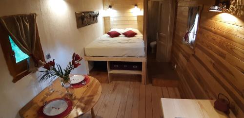 Charmante Roulotte atypique في Jaujac: غرفة صغيرة بها سرير وطاولة
