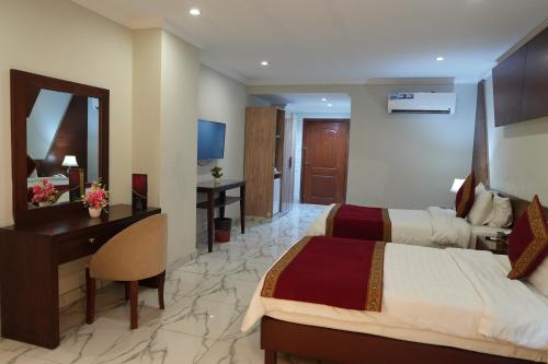 a hotel room with two beds and a desk and a mirror at Grand Millennium Hotel in Lahore