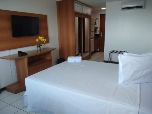 1 cama blanca grande en una habitación con TV en Ponta Negra Flats Partic, en Natal