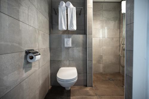 a bathroom with a toilet and towels on the wall at HOTELUX Amsterdam Airport Hotel in Hoofddorp