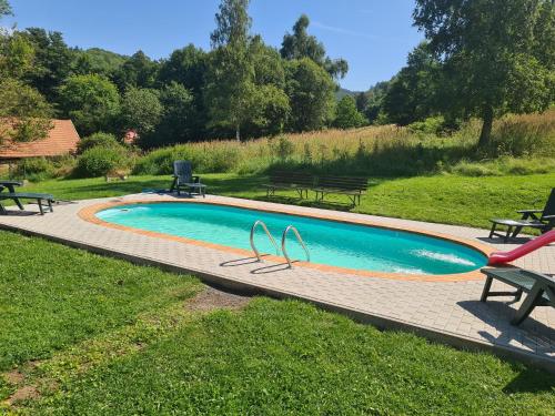 a swimming pool with picnic tables and benches around it at Penzion Kamzík in Česká Kamenice