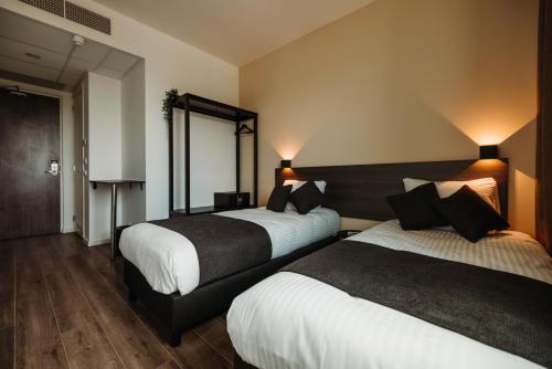 a hotel room with two beds and a mirror at HOTELUX Amsterdam Airport Hotel in Hoofddorp