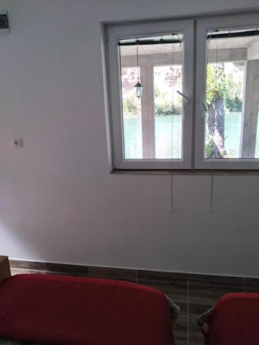 a room with a red couch and two windows at Apartman na Drini in Foča