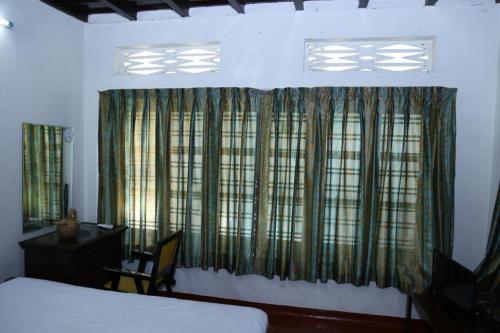 a bedroom with a bed and a desk and a window at Aqualillies Water Front Heritage Homestay in Kumarakom