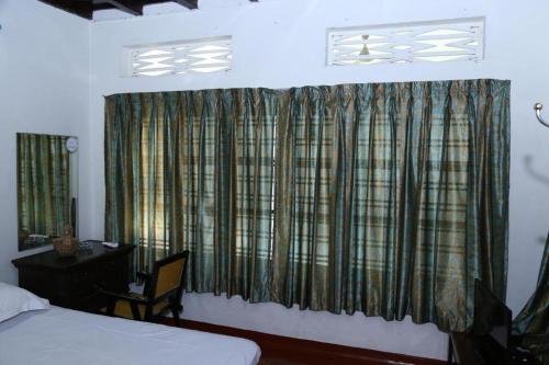 a bedroom with a bed and a desk and a window at Aqualillies Water Front Heritage Homestay in Kumarakom