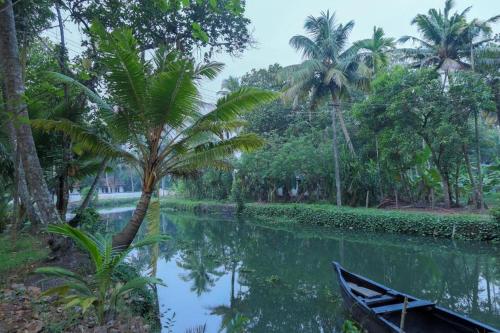 a boat on a river with a palm tree at Aqualillies Water Front Heritage Homestay in Kumarakom
