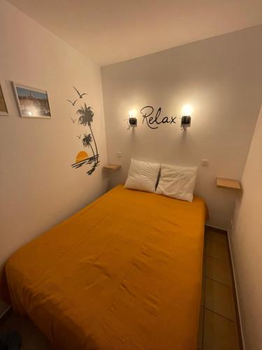 Cette petite chambre comprend un lit avec des draps orange. dans l'établissement Les Restanques - Grimaud, à Grimaud