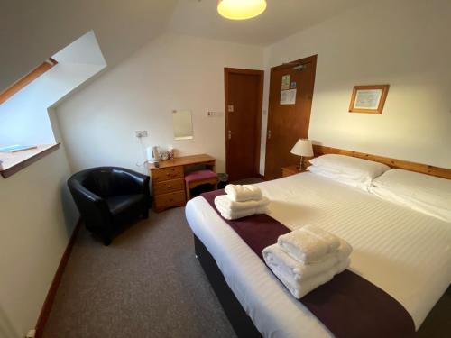 a hotel room with a bed and a chair at Smithton Hotel in Inverness