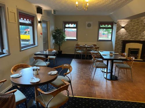 a restaurant with tables and chairs and a fireplace at Smithton Hotel in Inverness