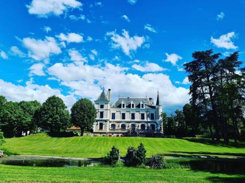 a white house on a green hill with a pond at Eclosion Château Hôtel & Restaurant in Saint-Paul-en-Jarez