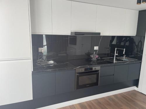 a kitchen with black counters and white cabinets at Perla Luxury Penthouse in Tirana