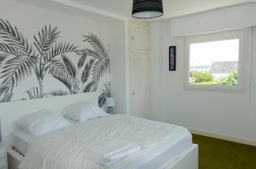 - une chambre avec un lit blanc orné d'une fresque murale de palmiers dans l'établissement Maison Golfe du Morbihan - Vue Mer - Plage à 600m - 6 Chambres, à Séné