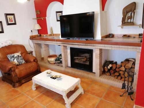 a living room with a fireplace and a flat screen tv at Casa Rural la Piedra del Cambrón in Villaverde de Guadalimar