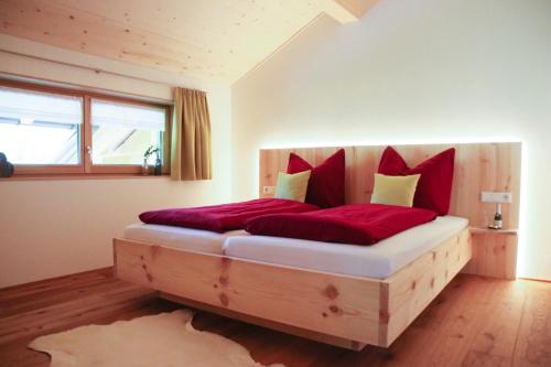 Un dormitorio con una gran cama de madera con almohadas rojas en Haus Bergquell, en Au im Bregenzerwald