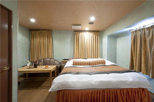 a bedroom with a large bed with a desk and a chair at ホテル ブランチャペルクリスマス 四日市 in Yokkaichi