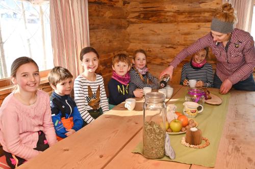 a group of children sitting around a table with a man preparing food at Haus Bergquell in Au im Bregenzerwald