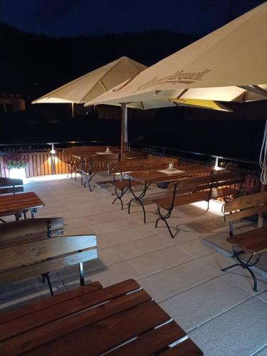 a row of wooden tables and benches with umbrellas at HORSKÝ PENZION U SPLAVU in Josefuv dul