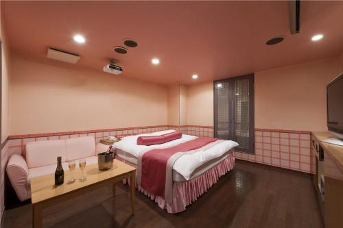 a bedroom with a bed and a table and a television at ホテル ブランチャペルクリスマス 四日市 in Yokkaichi