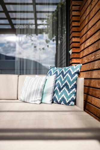 a couch with two pillows sitting next to a window at Boutique Hotel Eschenlohe in Schenna