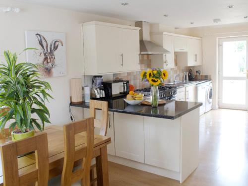 a kitchen with white cabinets and a black counter top at Webbys Windrush Walk in Bourton on the Water
