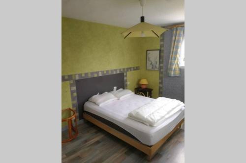 una camera da letto con un letto grande con cuscini bianchi di Agréable maison entre plage (900m) et forêt (600m) a Saint-Cast-le-Guildo