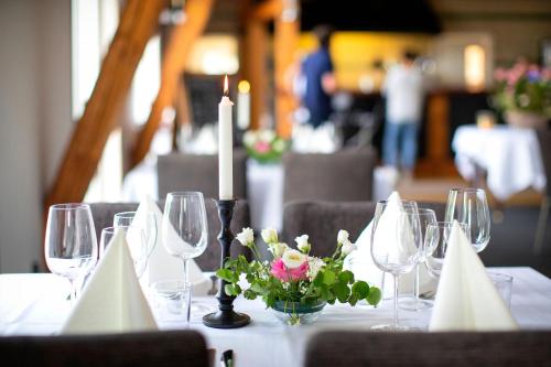 una mesa con vasos y una vela y flores en ella en Äppelgårdens Golfklubb, en Båstad