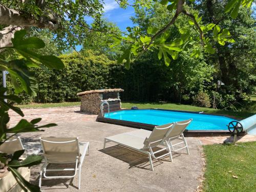 - une piscine avec 2 chaises, une table, une table et des chaises dans l'établissement Le Mas aux Arômes, à Puget