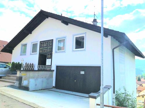 ein kleines weißes Haus mit einer schwarzen Garage in der Unterkunft Sanosueno 4 in Sonthofen