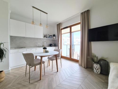 a kitchen and dining room with a table and chairs at Royal Sand Apartment in Gdańsk