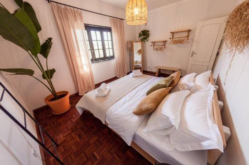 a bedroom with a white bed with a potted plant at Kodu Lodge - spacious 2 storey coastal home with balcony, sea view, garden & BBQ in Santo Isidoro