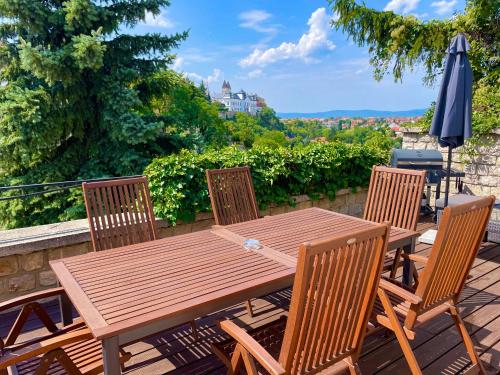 a wooden table and chairs on a deck with an umbrella at Terrace Apartman Prémium Belváros Jacuzzival in Veszprém