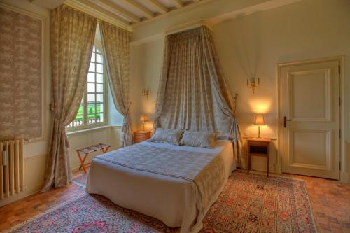a bedroom with a bed and a large window at Le Château d'Hauterives in Argentré