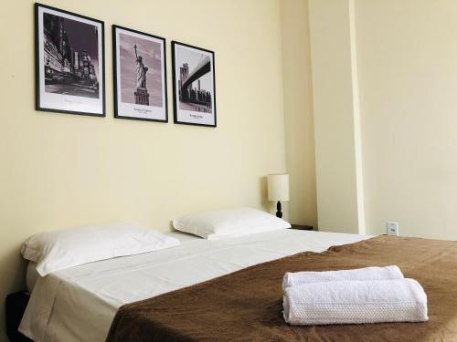 2 camas en un dormitorio con fotos en la pared en Apto Compacto com Ar no centro de Raul Soares-MG, en Raul Soares