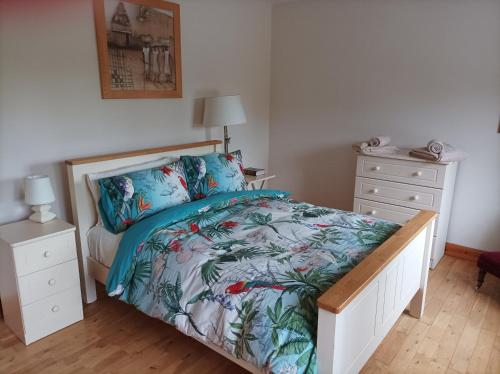 a bedroom with a bed and a dresser with a bedspread with flowers at Country Lane Homestay in Westport