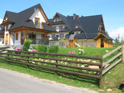 a house with a wooden fence in front of it at Domek Lilijka in Poronin
