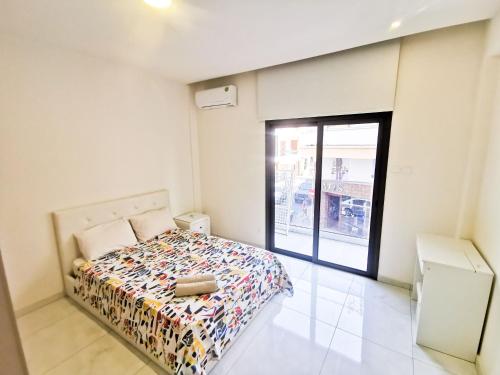 - une chambre avec un lit et une grande fenêtre dans l'établissement The White Pearl Apartment, à Larnaka