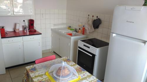 a small kitchen with a table and a white refrigerator at La casa du musée in Mulhouse