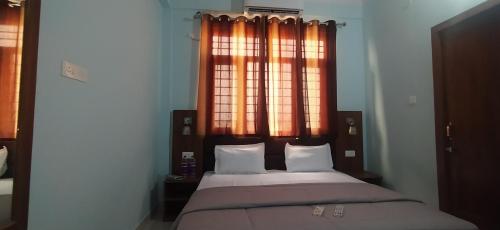a bed in a bedroom with a window with curtains at Hotel Comfort Inn Homestay in Dehradun