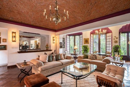 a large living room with couches and a chandelier at HOLT - Casa Parque Juárez in San Miguel de Allende