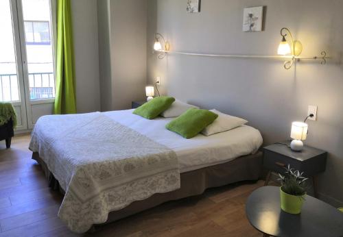 a bedroom with a large bed with two green pillows at Les Terrasses de David et Louisa in L'Isle-sur-la-Sorgue