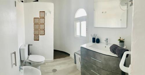 a white bathroom with a sink and a toilet at Azzurro house in Cotillo