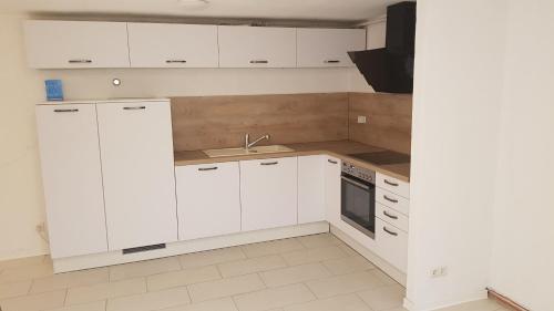 a kitchen with white cabinets and a sink at Air Rooms Hotel in Kelsterbach