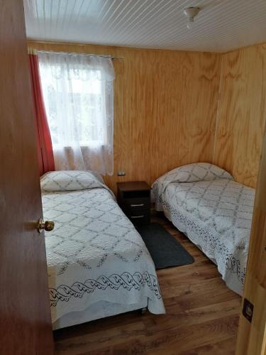 2 camas en una habitación pequeña con ventana en Cabaña María Quinchen, en Castro