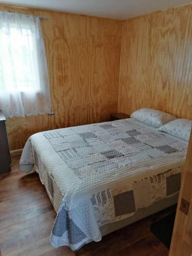um quarto com uma cama com uma colcha em Cabaña María Quinchen em Castro