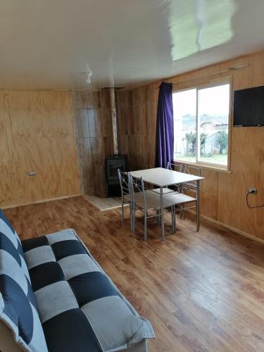 カストロにあるCabaña María Quinchenのベッドとテーブルと椅子のある部屋