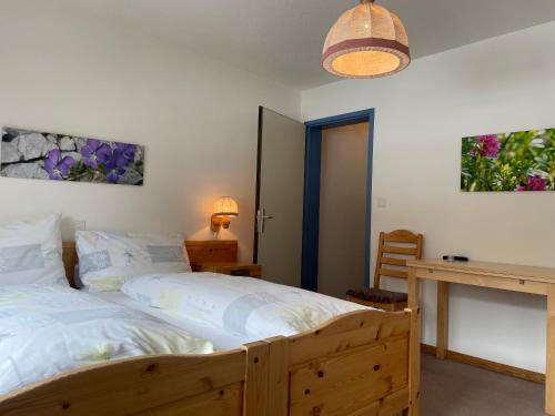Schlafzimmer mit einem Holzbett und einem Schreibtisch in der Unterkunft Landhuus Frauenkirch in Frauenkirch