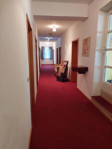 a hallway with a red carpeted floor and a window at Der Heurige im Gasthaus zum Löwen in Freising