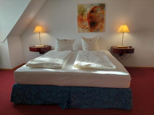 two beds in a hotel room with two lamps at Der Heurige im Gasthaus zum Löwen in Freising